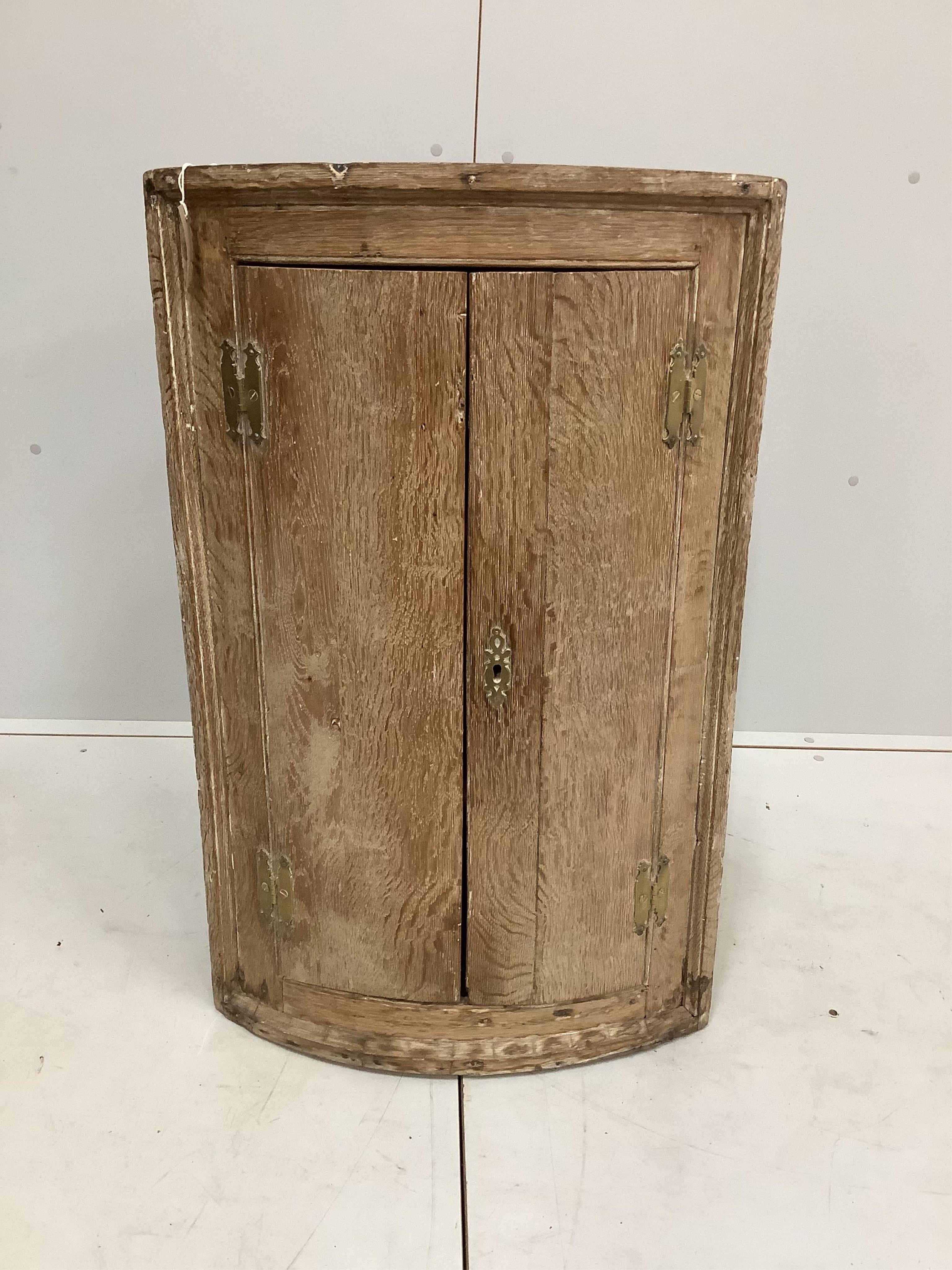 An 18th century oak bow front hanging corner cupboard, width 56cm, depth 38cm, height 91cm